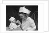 1930s little girl playing nurse with doll spoonful of medicine by Anonymous