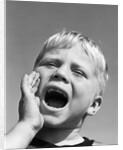 1950s blond boy with eyes closed and hand cupping a wide open mouth shouting by Anonymous