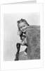 1940s little girl holding doll peeking around side of chair by Anonymous