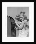 1930s 1940s child blond little girl with pigtails putting letter into mail box, looking at camera by Anonymous