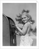 1930s 1940s child blond little girl with pigtails putting letter into mail box, looking at camera by Anonymous