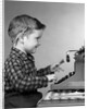 1950s smiling young boy typing on typewriter by Anonymous