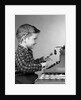 1950s smiling young boy typing on typewriter by Anonymous