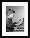 1950s smiling young boy typing on typewriter by Anonymous