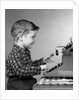 1950s smiling young boy typing on typewriter by Anonymous