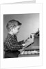 1950s smiling young boy typing on typewriter by Anonymous