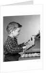 1950s smiling young boy typing on typewriter by Anonymous