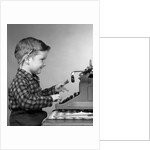 1950s smiling young boy typing on typewriter by Anonymous