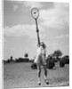 1930s girl playing tennis jumping to hit ball overhead by Anonymous