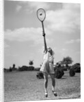 1930s girl playing tennis jumping to hit ball overhead by Anonymous
