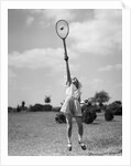 1930s girl playing tennis jumping to hit ball overhead by Anonymous