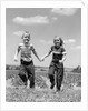 1950s boy girl running grassy farm field holding hands by Anonymous