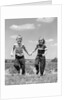1950s boy girl running grassy farm field holding hands by Anonymous