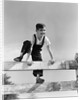 1940s brunette boy wearing overalls climbing over fence by Anonymous