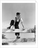 1940s brunette boy wearing overalls climbing over fence by Anonymous