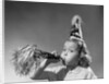 1950s girl wearing party hat blowing into noise maker looking at camera by Anonymous