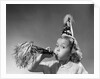 1950s girl wearing party hat blowing into noise maker looking at camera by Corbis