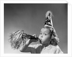 1950s girl wearing party hat blowing into noise maker looking at camera by Corbis