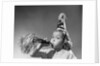 1950s girl wearing party hat blowing into noise maker looking at camera by Anonymous
