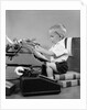 1950s child typing sitting at typewriter by Anonymous