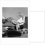 1950s child typing sitting at typewriter by Anonymous