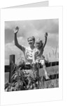1930s girl sitting on fence with woman next to her in field waving by Anonymous