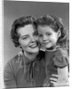 1950s girl daughter smiling hugging woman mother cheek to cheek together by Anonymous