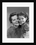 1950s girl daughter smiling hugging woman mother cheek to cheek together by Anonymous