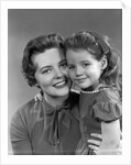 1950s girl daughter smiling hugging woman mother cheek to cheek together by Anonymous