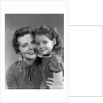 1950s girl daughter smiling hugging woman mother cheek to cheek together by Anonymous