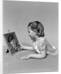 1940s child little girl looking at framed picture of her father a soldier in uniform by Anonymous