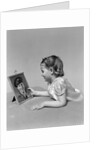 1940s child little girl looking at framed picture of her father a soldier in uniform by Anonymous