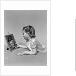 1940s child little girl looking at framed picture of her father a soldier in uniform by Anonymous