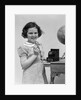 1930s child smiling girl putting money coin into toy cash register bank by Anonymous