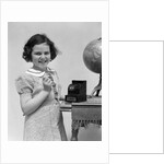 1930s child smiling girl putting money coin into toy cash register bank by Anonymous