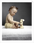 1940s 1950s baby sitting touching toy dog by Anonymous