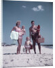 1950s family man woman mother father children boy girl son daughter standing sandy beach with toys and picnic basket by Anonymous