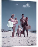 1950s family man woman mother father children boy girl son daughter standing sandy beach with toys and picnic basket by Anonymous
