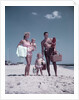1950s family man woman mother father children boy girl son daughter standing sandy beach with toys and picnic basket by Anonymous