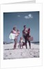 1950s family man woman mother father children boy girl son daughter standing sandy beach with toys and picnic basket by Anonymous