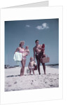 1950s family man woman mother father children boy girl son daughter standing sandy beach with toys and picnic basket by Anonymous