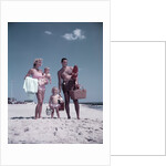 1950s family man woman mother father children boy girl son daughter standing sandy beach with toys and picnic basket by Anonymous