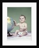 1960s smiling baby girl sitting in diapers hand touching world globe by Anonymous