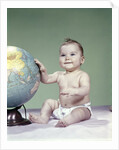 1960s smiling baby girl sitting in diapers hand touching world globe by Anonymous