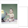 1960s smiling baby girl sitting in diapers hand touching world globe by Anonymous