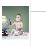 1960s smiling baby girl sitting in diapers hand touching world globe by Anonymous