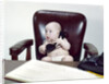 1960s chubby baby sitting in leather chair at office desk holding telephone by Anonymous