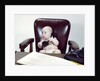 1960s chubby baby sitting in leather chair at office desk holding telephone by Anonymous