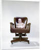1960s chubby baby in diaper sitting in office executive chair by Anonymous