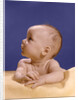 1960s portrait of baby on yellow blanket resting on folded arms head turned to right looking up by Anonymous